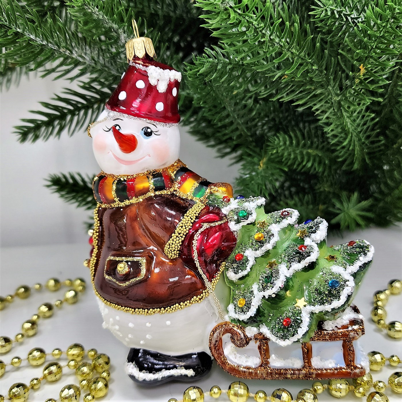 фото Стеклянная елочная игрушка Снеговик тянет саночки