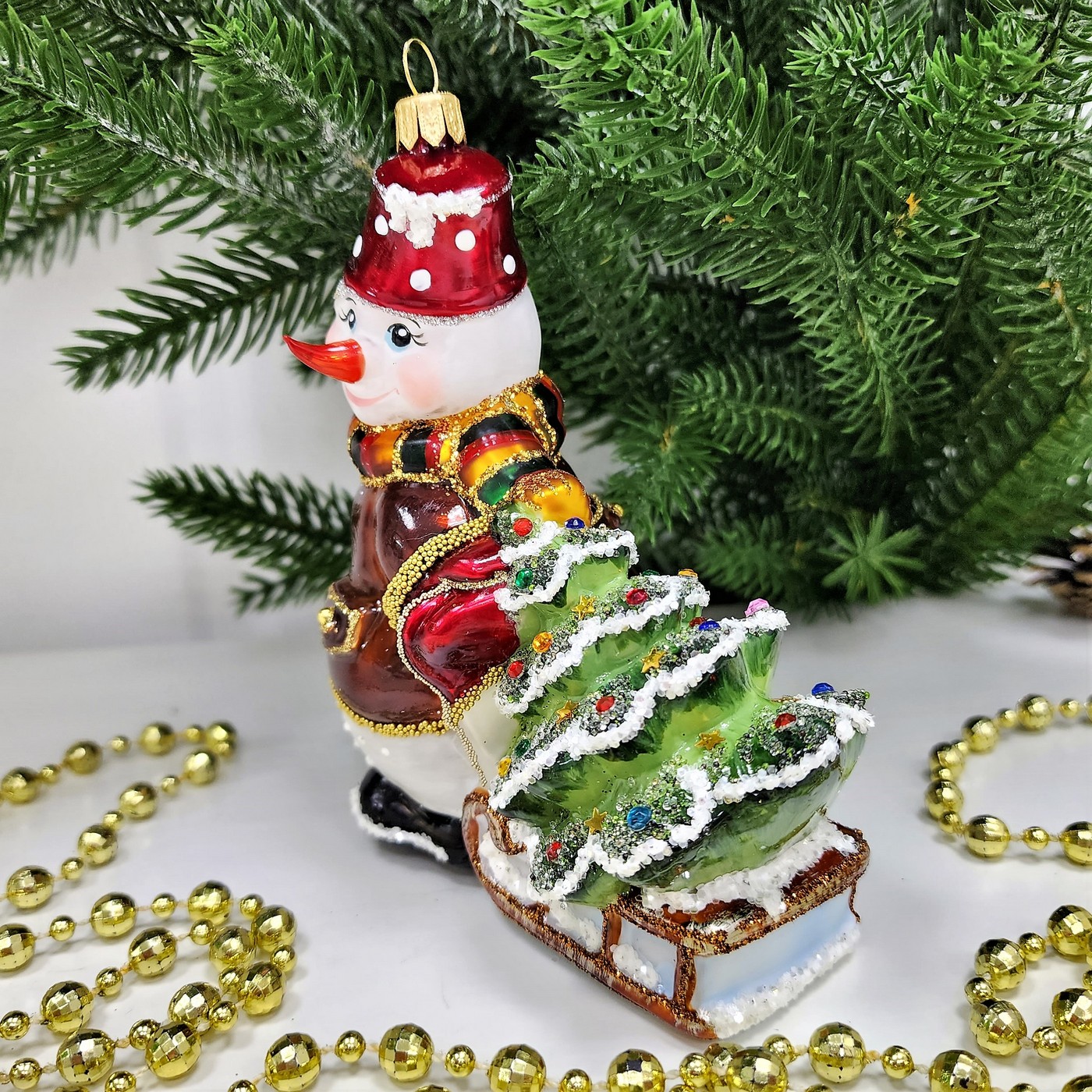 фото Стеклянная елочная игрушка Снеговик тянет саночки
