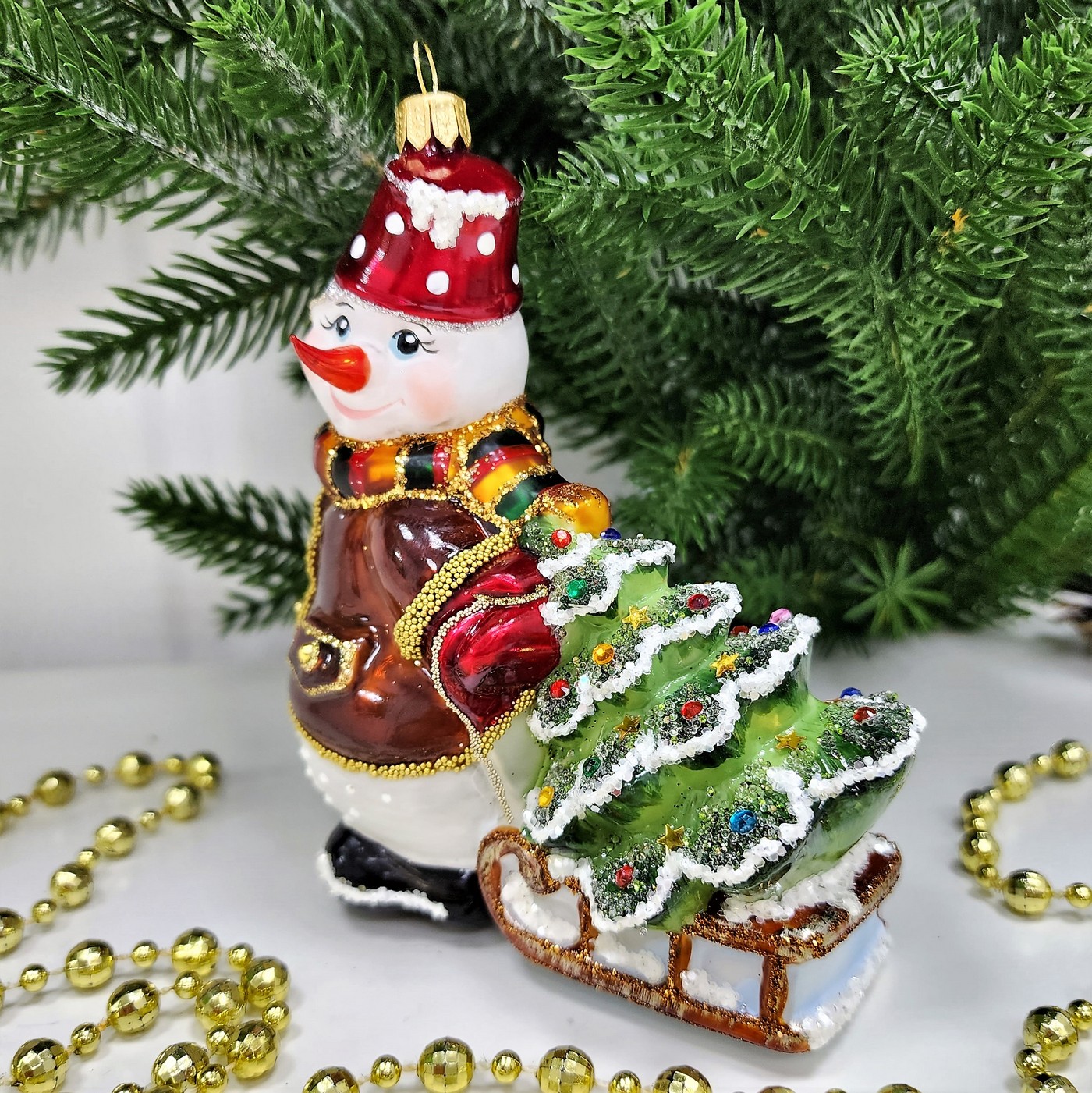 фото Стеклянная елочная игрушка Снеговик тянет саночки