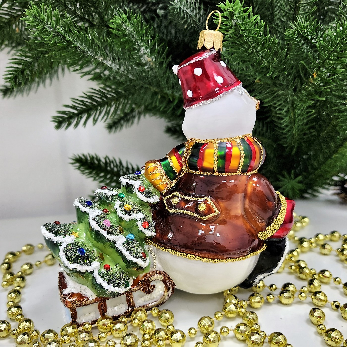 фото Стеклянная елочная игрушка Снеговик тянет саночки