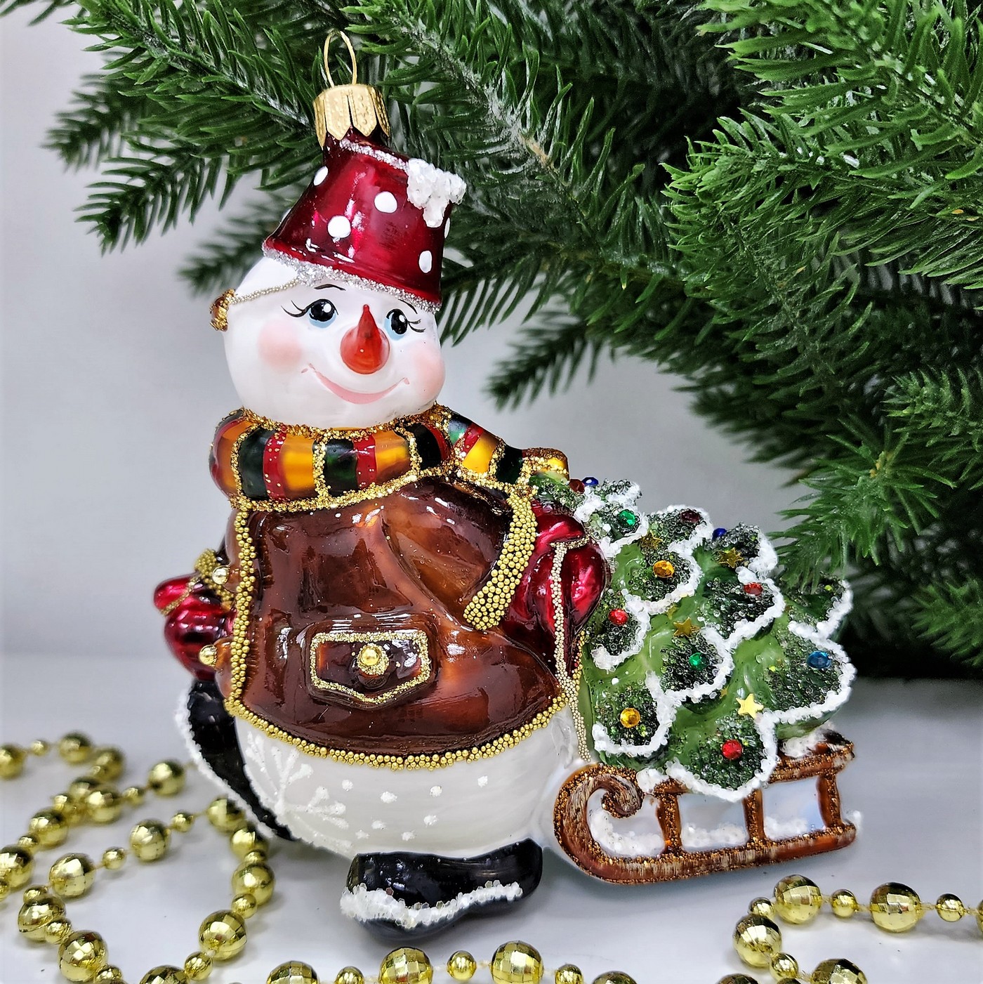 фото Стеклянная елочная игрушка Снеговик тянет саночки