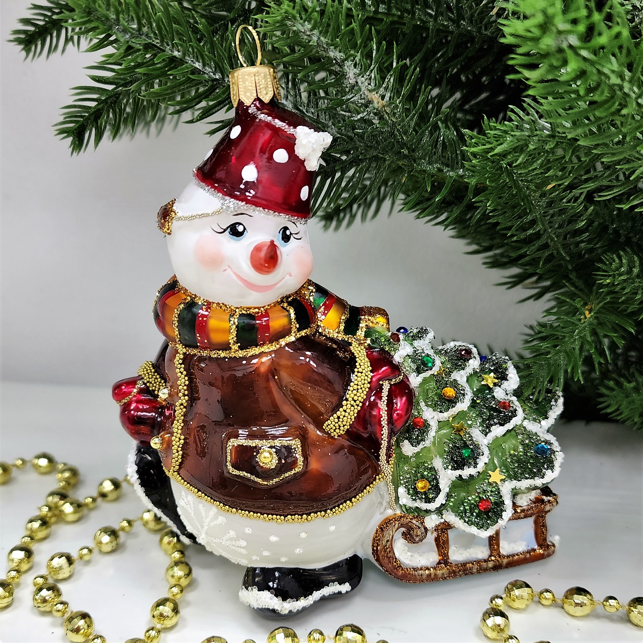 фото Стеклянная елочная игрушка Снеговик тянет саночки