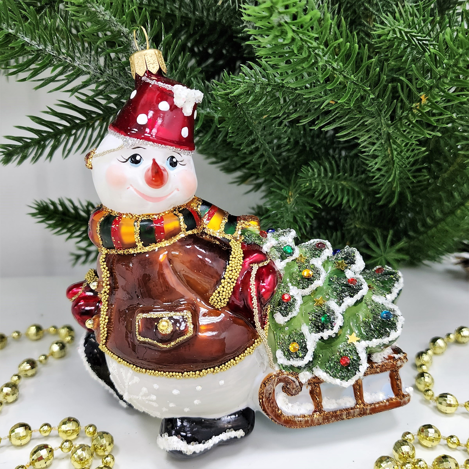 фото Стеклянная елочная игрушка Снеговик тянет саночки