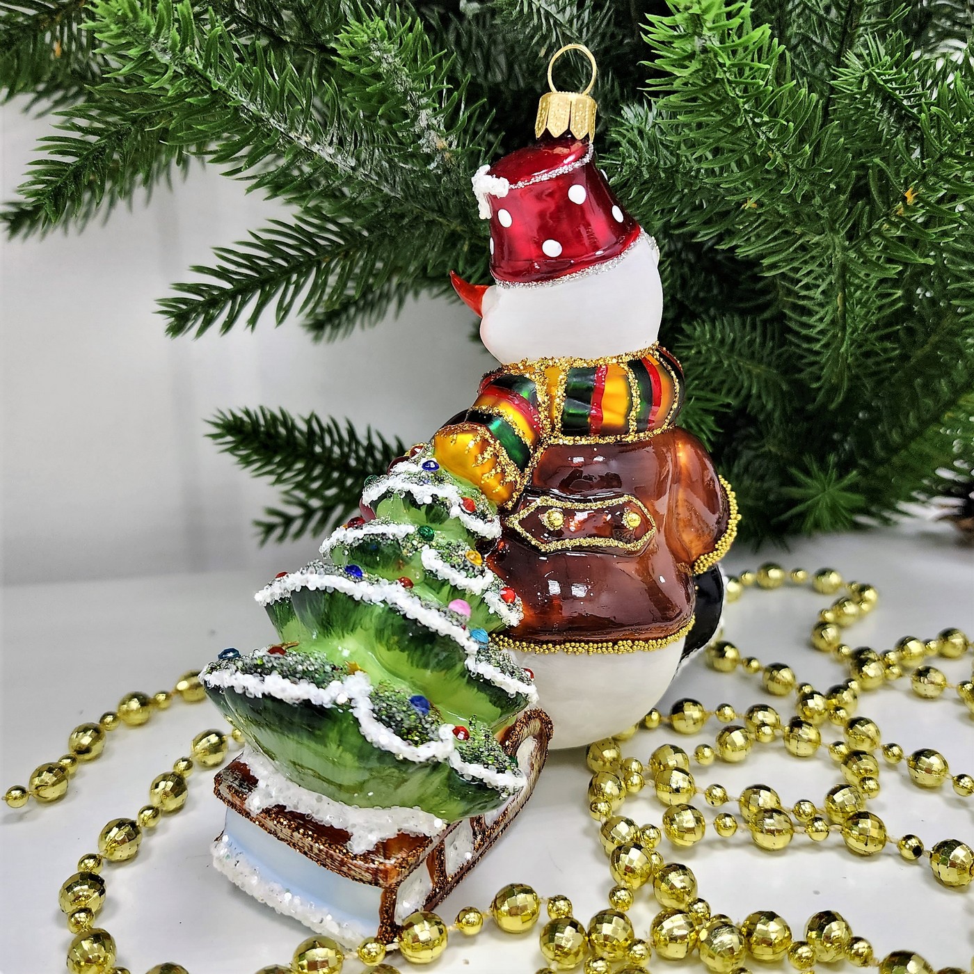 фото Стеклянная елочная игрушка Снеговик тянет саночки