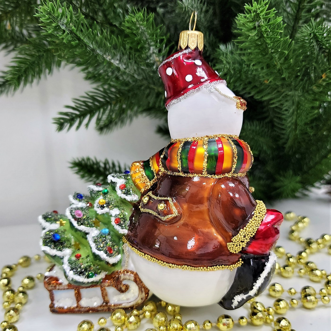 фото Стеклянная елочная игрушка Снеговик тянет саночки