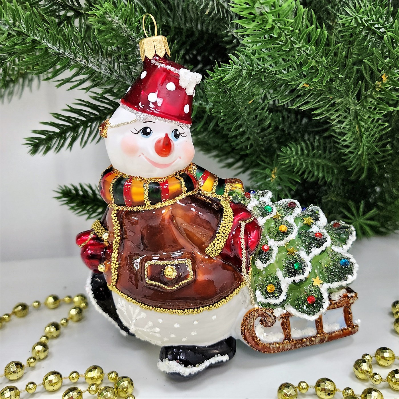 фото Стеклянная елочная игрушка Снеговик тянет саночки