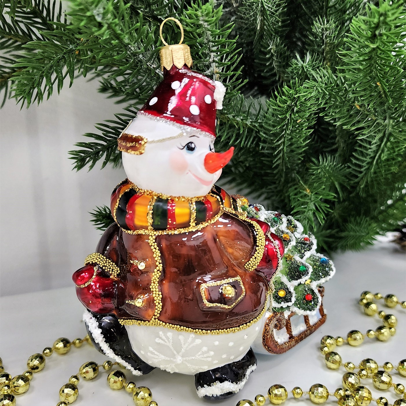 фото Стеклянная елочная игрушка Снеговик тянет саночки