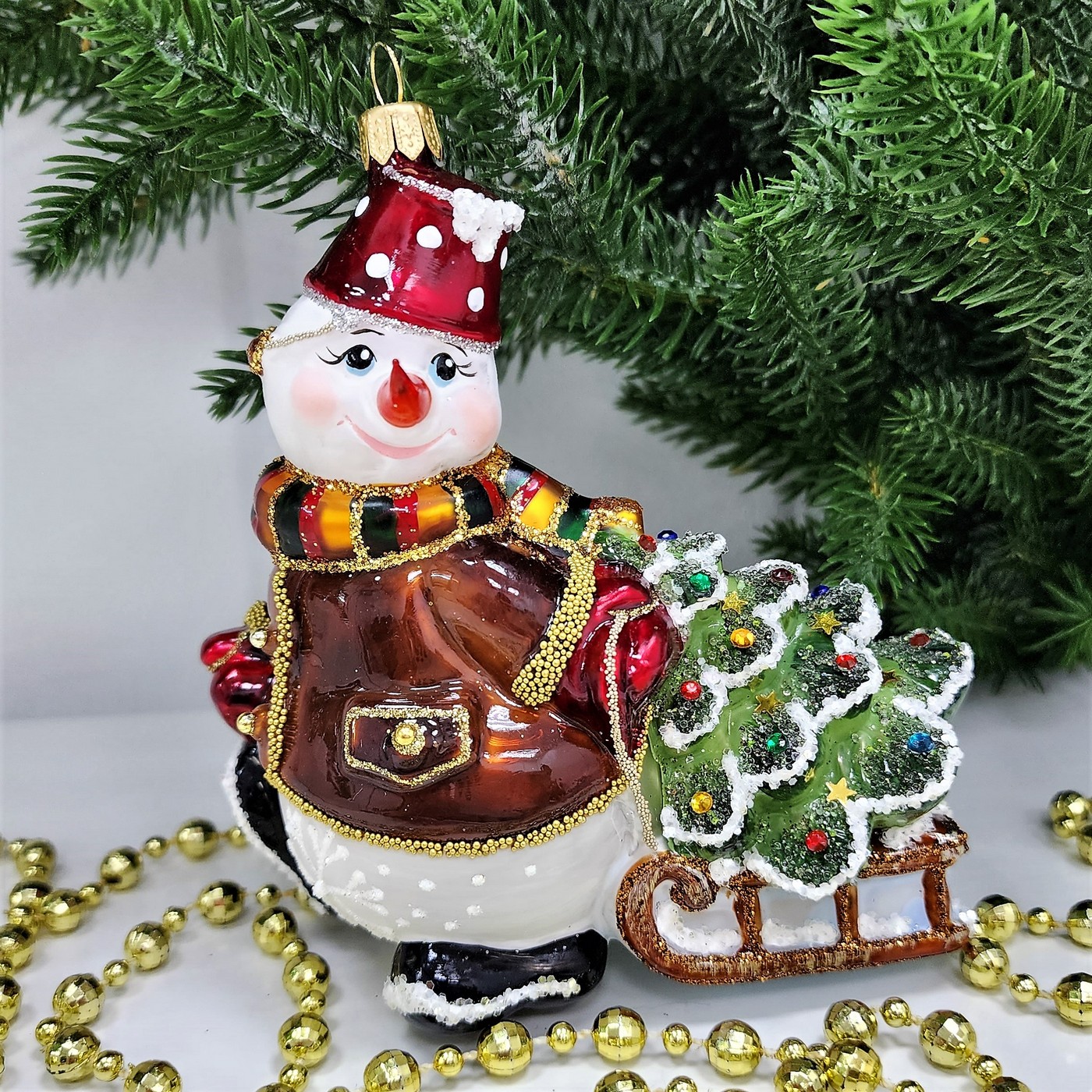 фото Стеклянная елочная игрушка Снеговик тянет саночки