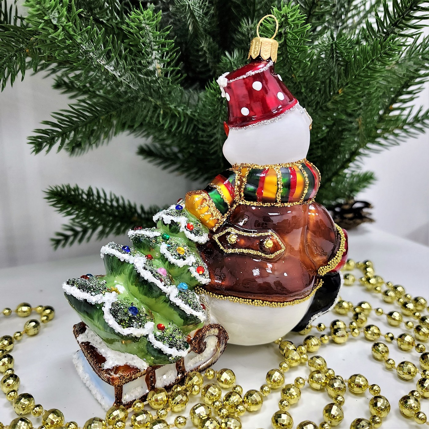 фото Стеклянная елочная игрушка Снеговик тянет саночки