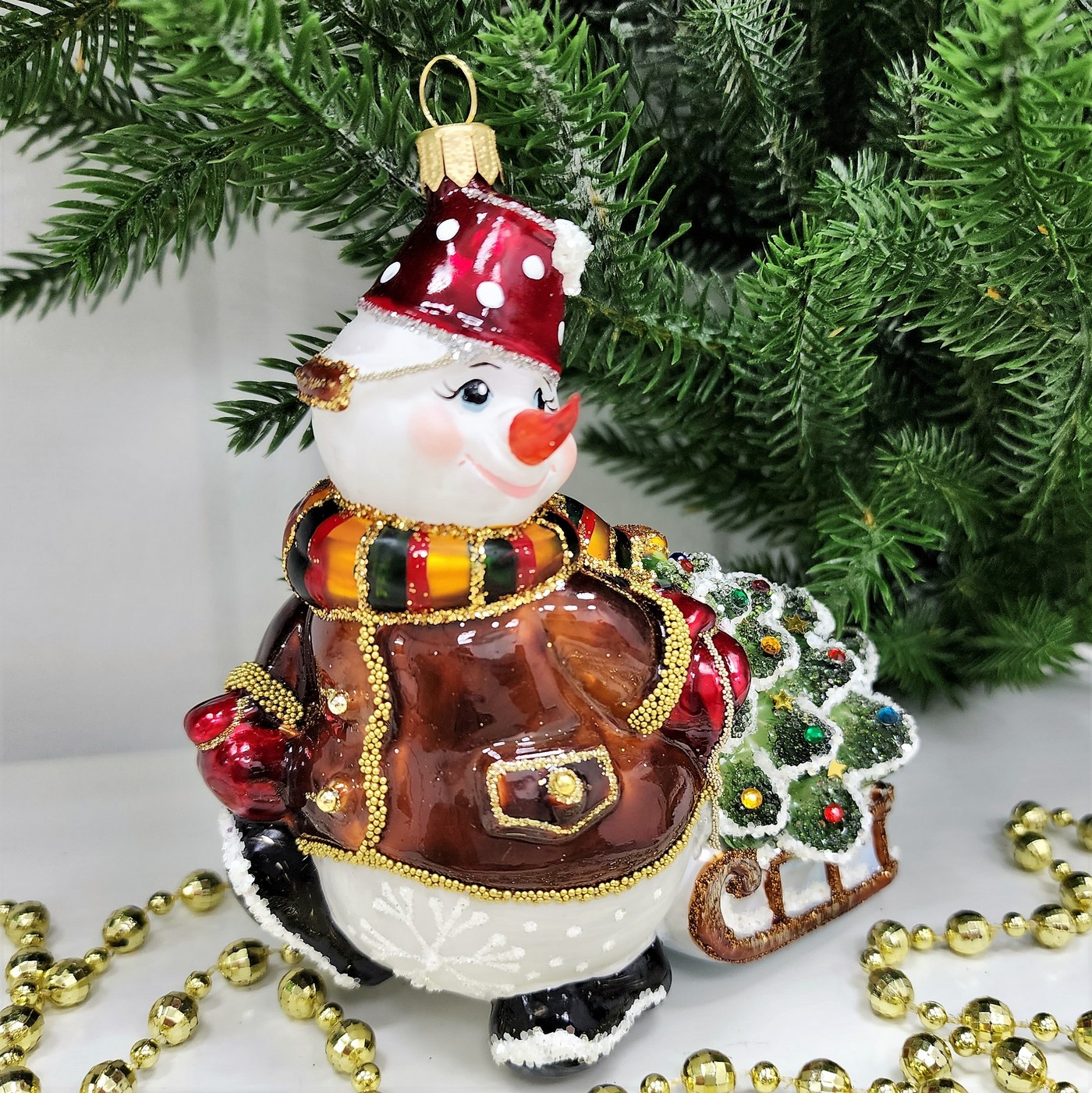 фото Стеклянная елочная игрушка Снеговик тянет саночки